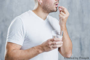 Junger Mann beim Einnehmen von Magnesiumtabletten