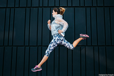 Sportliche, junge Frau in Sportoutfit beim Springen.
